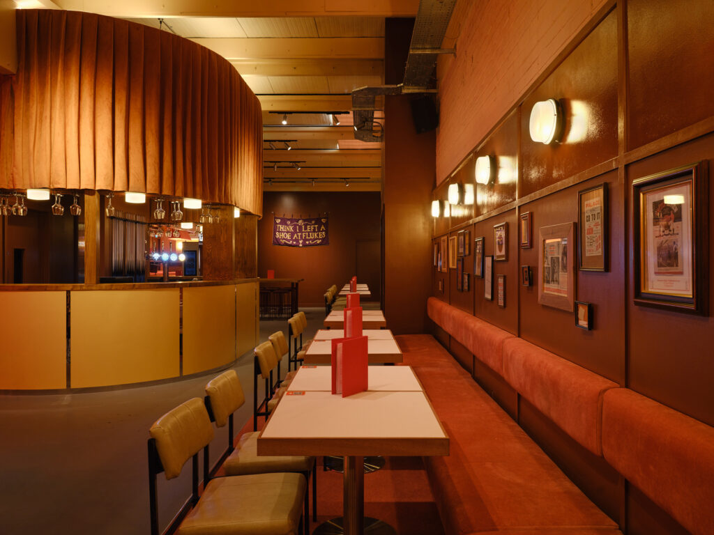 Games hall supported with vintage-inspired commercial lighting design that brings an atmospheric, slightly grungy old-English games room aesthetic in London, United Kingdom.