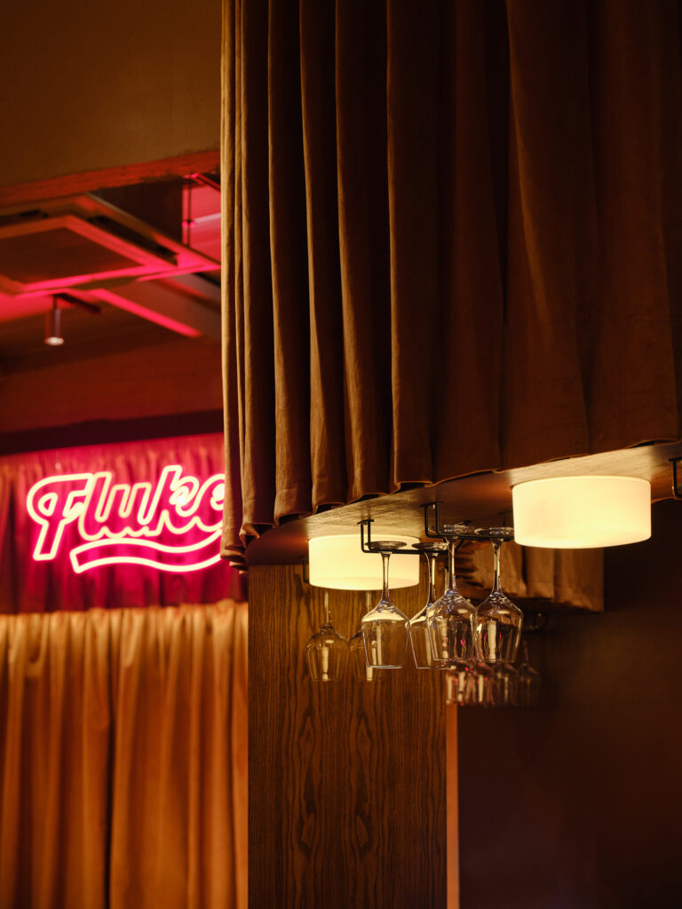 Vintage-style low-level decorative lighting design with ambient spotlights in the bar area at Flukes, Big Penny Social, London. Commercial lighting design from Michael Grubb Studio.